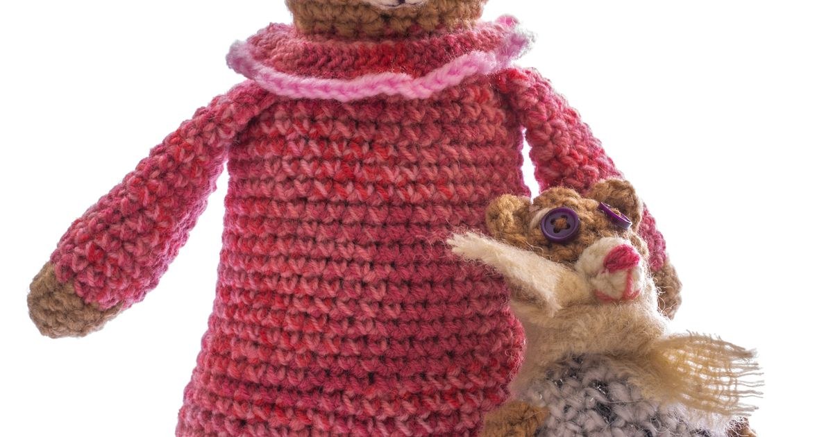 Charming handcrafted crochet bear wearing a pink dress, holding a mini teddy.