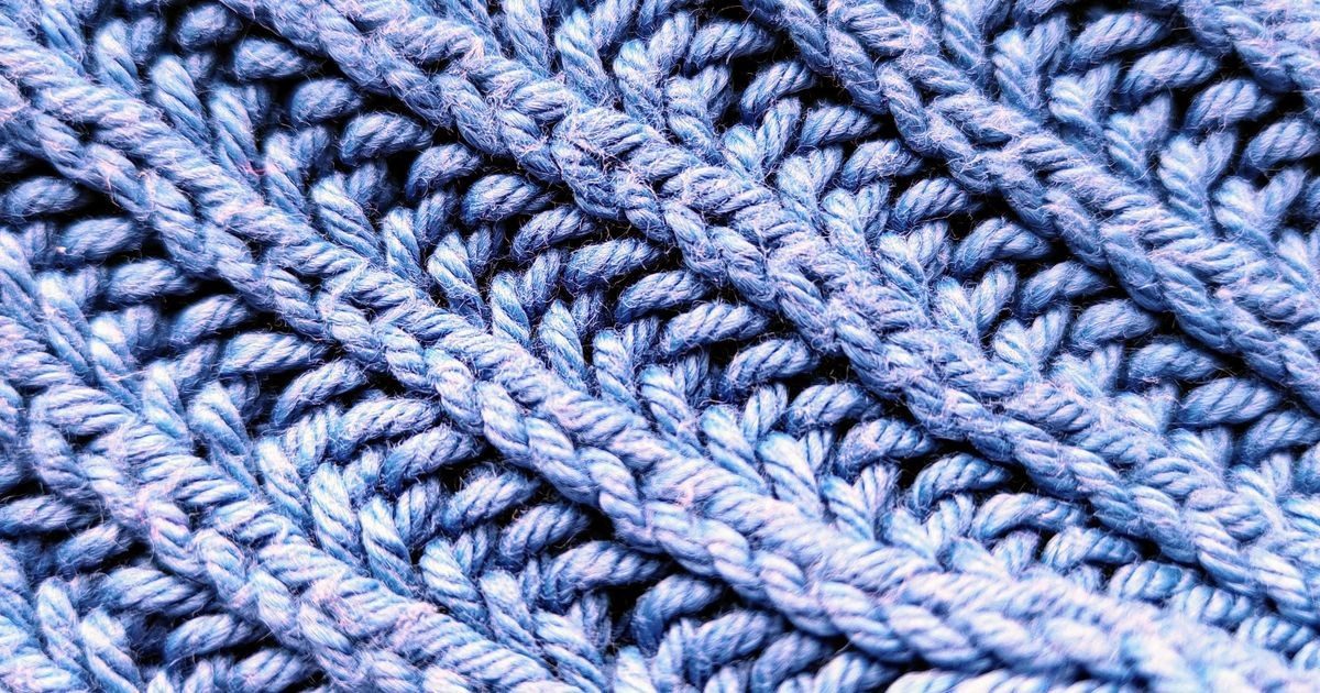 Detailed close-up of a blue knitted wool pattern, showcasing texture and craftsmanship.
