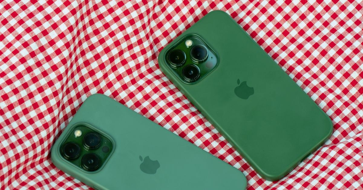 Two green smartphones with cases on red checkered fabric.