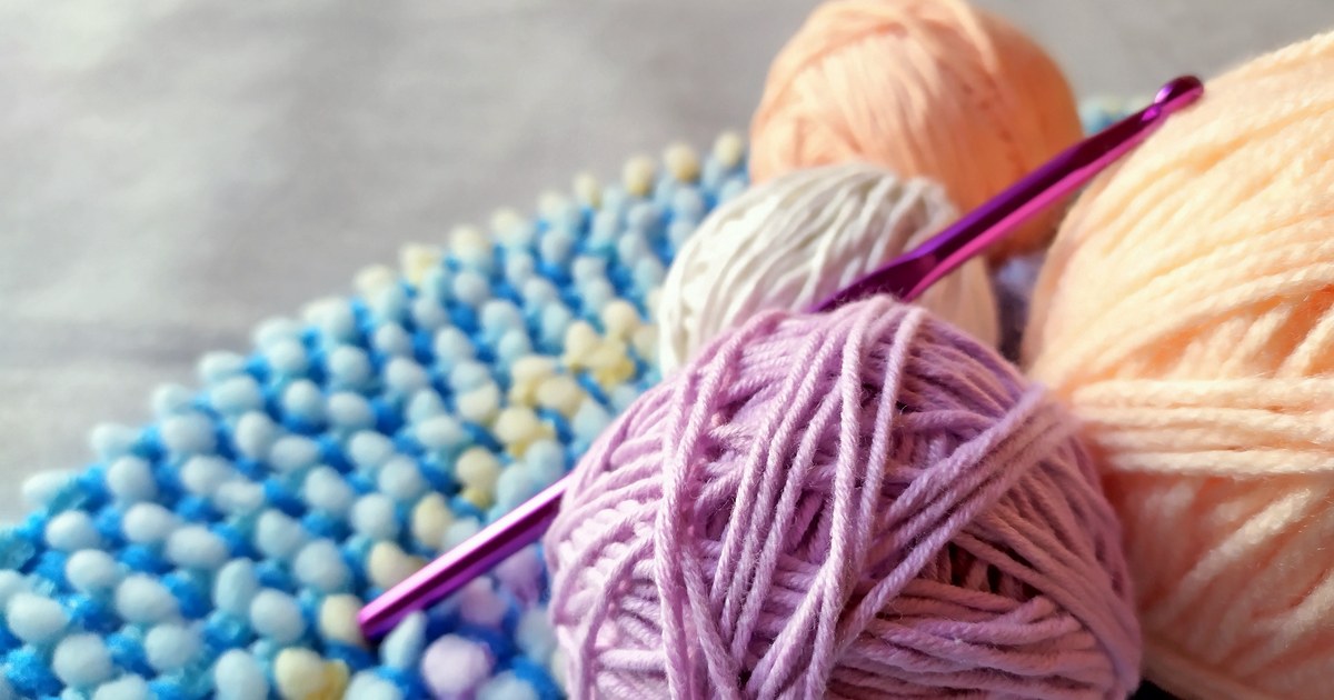 Vibrant yarn and crochet hook on textured fabric. Perfect for craft projects.