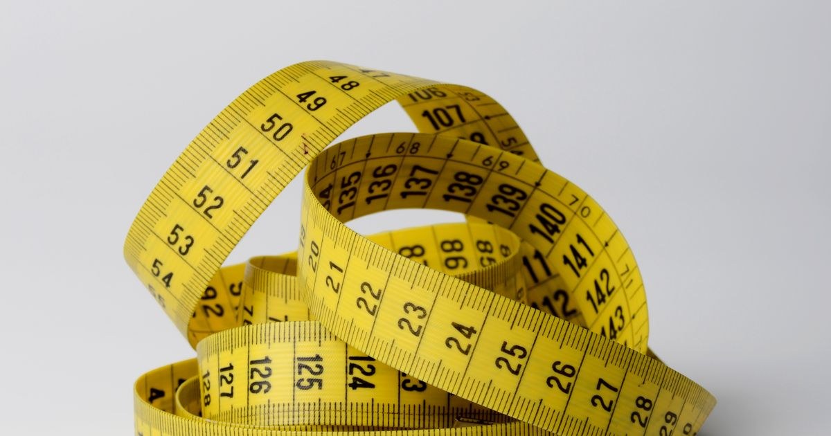 A close-up image of a coiled yellow measuring tape displaying numbers clearly.