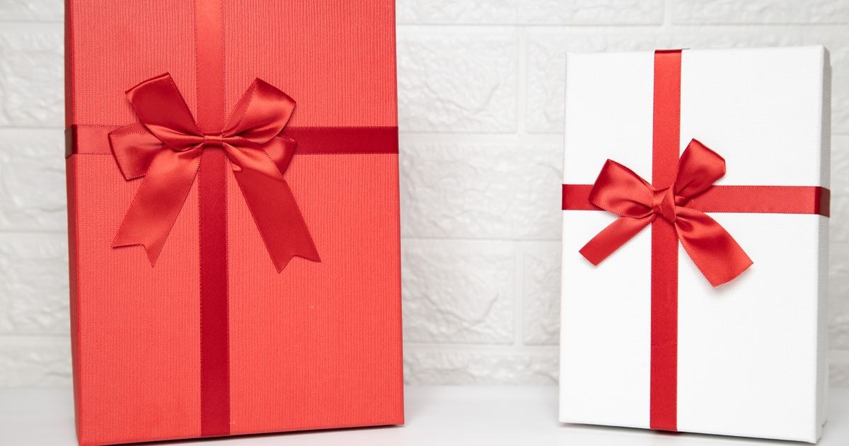 Two stylish gift boxes with red ribbons on a white indoor background, perfect for celebrations.