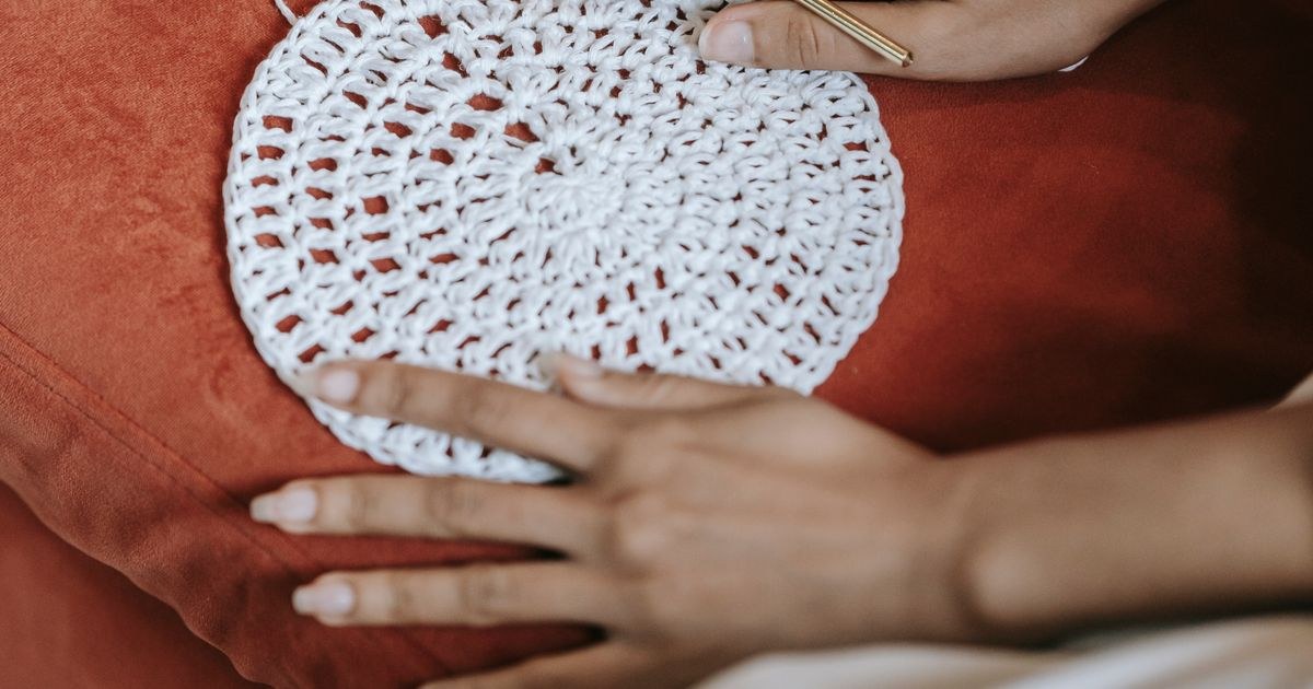 Hands engaging in a crochet hobby, creating a round white pattern on a warm background.