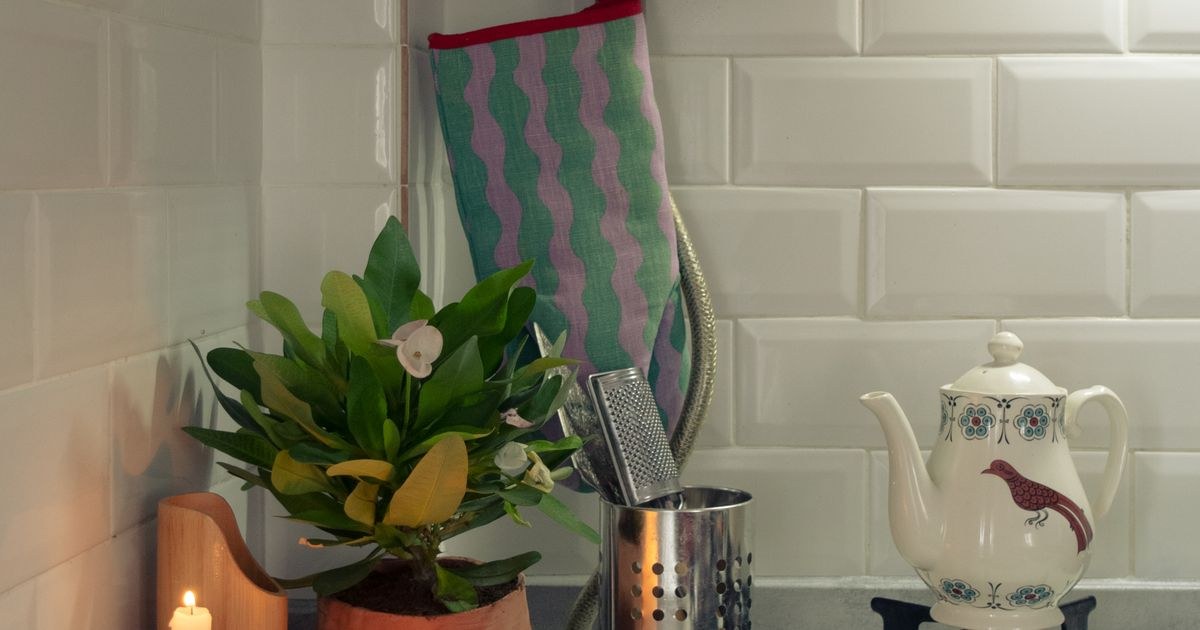 A warm and inviting kitchen counter with a teapot, candles, and potted plant for a cozy ambiance.