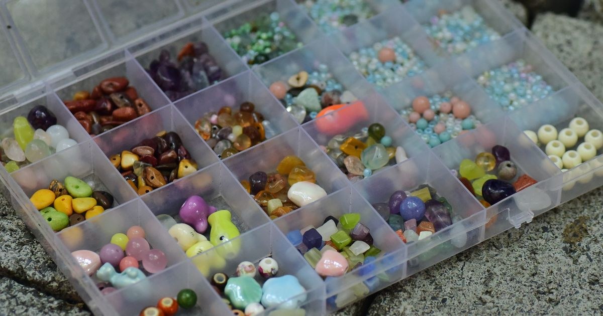 Top view of a transparent storage box filled with colorful assorted beads for crafts and jewelry making.