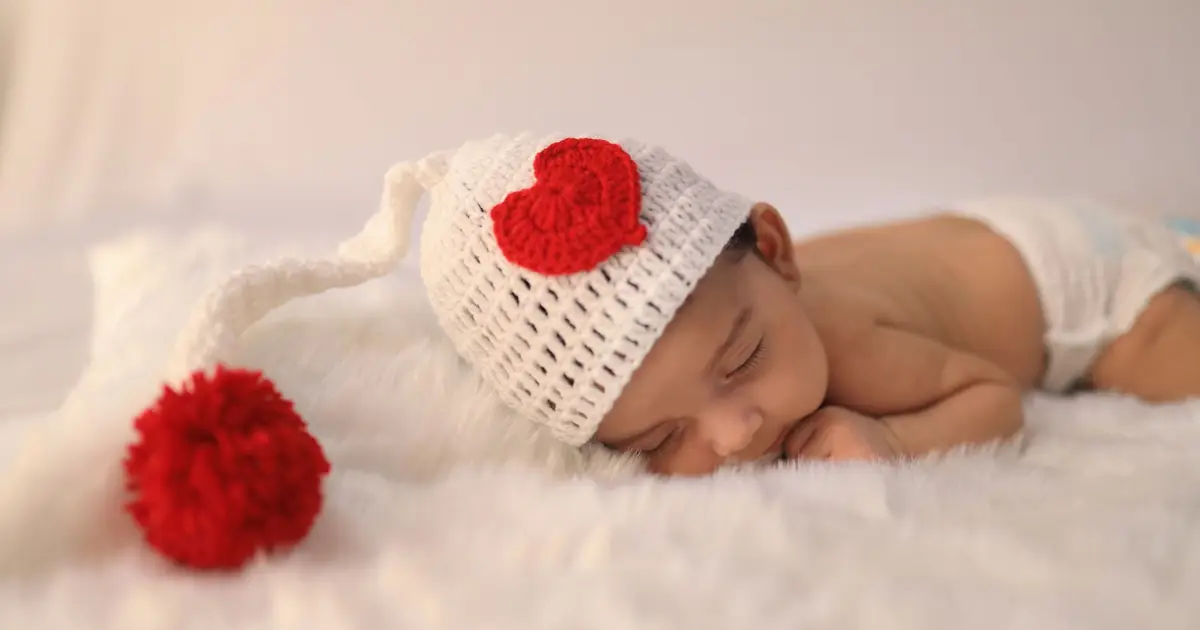 Close-up of a peaceful sleeping baby wearing a cozy crochet hat with heart design.