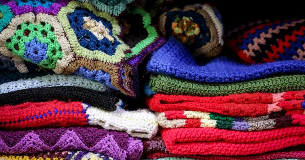 A vibrant stack of vintage crochet blankets showcasing intricate patterns and colorful designs.