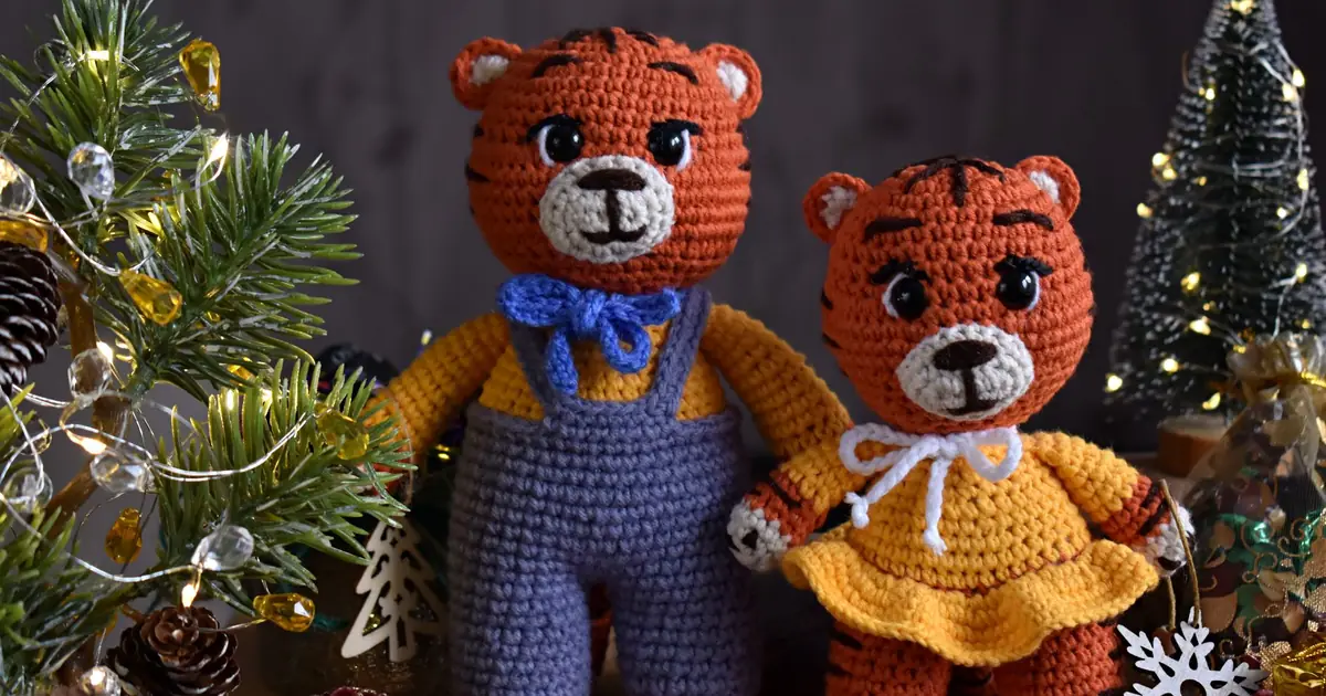 Close-up of two crocheted tiger toys surrounded by festive Christmas decorations.